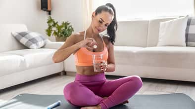 Young woman i sportswear with magnesia effervescent tablet and glass of pure or mineral water.