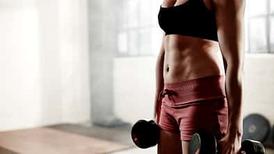 Eine trainierte Frau mit Kurzhanteln in den Händen