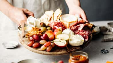 Eine Frau serviert eine Mezze-Platte auf einem Tisch