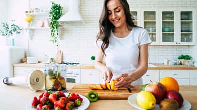 Beautiful woman making fruits smoothies with blender.