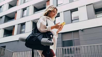 Happy Sporty Woman in a White Sweatshirt Using a Mobile Phone Outdoors Happy Sporty Woman in a White Sweatshirt Using a Mobile Phone Outdoors