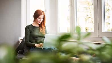 Eine rothaarige Frau arbeitet am Laptop