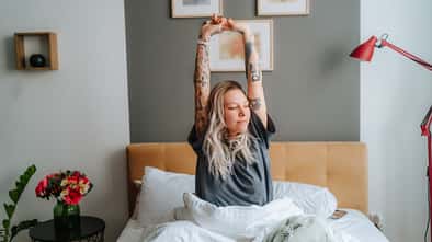 Eine Frau sitzt im Bett und räkelt sich