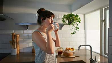 Woman drinking from mug in zero waste kitchen.