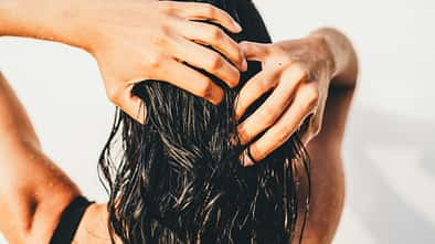 A beautiful unrecognizable woman washing hair in an outdoor shower