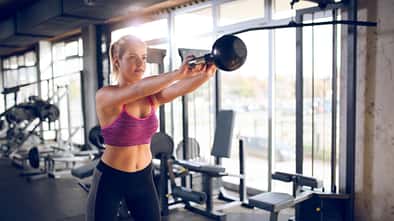 Young woman doing kettlebell exercise at gym