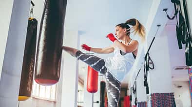 Frau kickt gegen einen Boxsack im Boxstudio