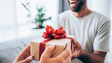 Cheerful young man receiving a gift from his girlfriend.