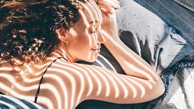 Frau liegt im Halbschatten in der Sonne Frau liegt im Halbschatten in der Sonne