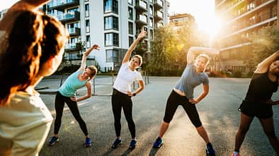 Eine Sportgruppe von Frauen wärmt sich im der Stadt vor dem Laufen gehen auf Eine Sportgruppe von Frauen wärmt sich im der Stadt vor dem Laufen gehen auf