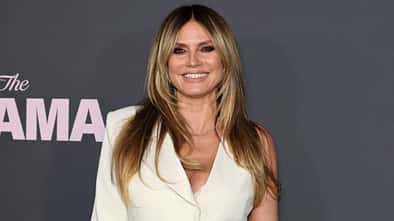 Heidi Klum lächelt im Weißen Kleid in die Kamera 