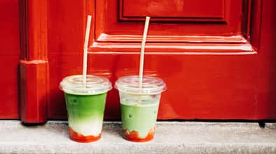 Zwei Iced Strawberry Matcha Lattes vor einer roten Haustür