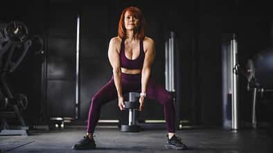 Eine trainierte Frau macht Kniebeugen mit einer Kettlebell