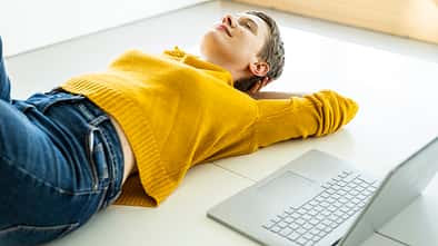 Woman relaxing on the floor with a laptop in a bright office space