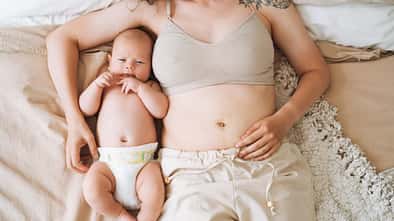 Frau liegt mit ihrem Baby im Bett