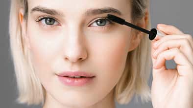 Frau schminkt sich und trägt Mascara auf