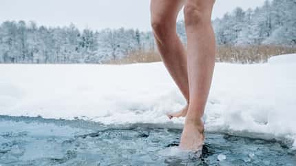 Eisbaden, Sauna, See im Winter, Abkühlung, Saunieren Frau auf dem Weg in einen eiskalten See im Winter. Es sind nur ihre Beine zu sehen.