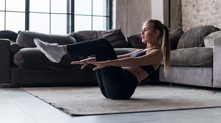 Muskelaufbau, Muskeltraining, Bodyweight Training Frau macht eine Bauchübung im Wohnzimmer.