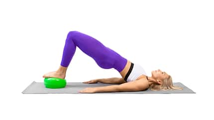 Glute Brigde, Beckenheben, Pilates Frau bei der Übung Hüftheben mit den Füßen auf dem Pilates-Ball