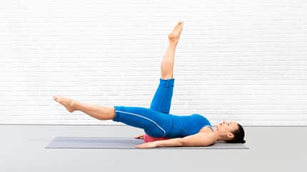 Circles, Pilates, Pilates-Ball Frau macht mit gestreckten Beinen Kreise in die Luft während ihr unterer Rücken auf dem Pilates-Ball ruht