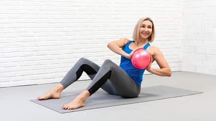 Russian Twist, Pilates-Ball Frau macht Russian Twist mit einem Pilates-Ball.