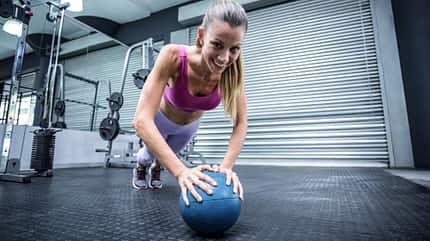 Core-Training, Stütz, Fitnessball Frau stützt mit den Händen auf einem Medizinball.