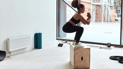 Box Jump Frau macht Sprung auf eine Box.