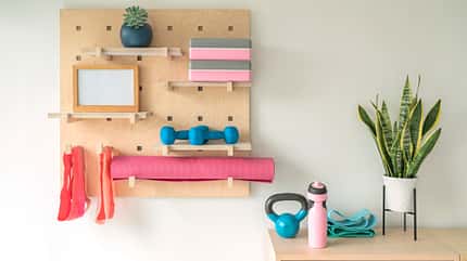 Homegym-Ausstattung: Matte, Bänder und Kettlebell ordentlich angeordnet im Regal