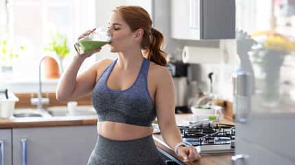 30-40 years,adults,caucasian,dishes,female,glass,health,healthy,home,juice,mid adults,nutrition,redheaded,sportswear,three-quarter length,training,united kingdom,woman Redhead woman drinking healthy milkshake after working out at home