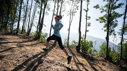 Joggerin läuft durch lichtdurchfluteten Wald