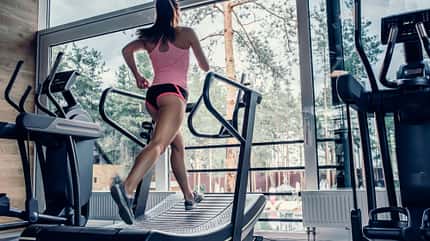 Frau trainiert auf einem Laufband mit gebogener Lauffläche Frau trainiert auf einem Laufband mit gebogener Lauffläche