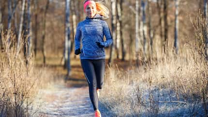 Frau läuft im Winter durch Wald- und Heide