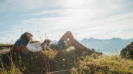 Wandern Frau macht beim Wandern eine Pause und liegt im Gras.