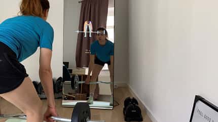 Redakteurin Martina trainiert mit einer Langhantel vor einem digitalen Fitnessspiegel Redakteurin Martina trainiert mit einer Langhantel vor einem digitalen Fitnessspiegel