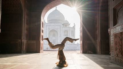 Junge Frau praktiziert Yoga in Indien im berühmten Taj Mahal bei Sonnenaufgang Junge Frau praktiziert Yoga in Indien im berühmten Taj Mahal bei Sonnenaufgang