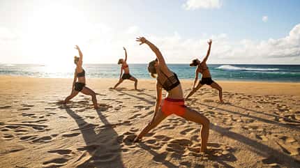 Freunde praktizieren Yoga am Strand Freunde praktizieren Yoga am Strand