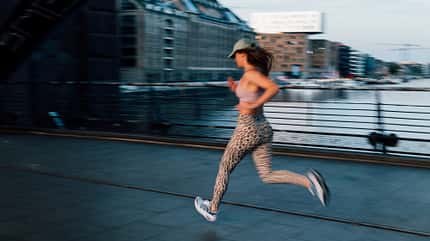 Eine Frau joggt über eine Straße in Sportkleidung Eine Frau joggt über eine Straße in Sportkleidung