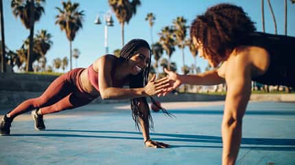 Bild von zwei jungen Frauen, die Cross-Trainingsübungen auf den Basketballplätzen in der Nähe des Venice Beach in Los Angeles, Kalifornien, machen. Bild von zwei jungen Frauen, die Cross-Trainingsübungen auf den Basketballplätzen in der Nähe des Venice Beach in Los Angeles, Kalifornien, machen.