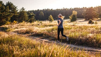Eine Frau joggt durch Herbstlandschaft Eine Frau joggt durch Herbstlandschaft