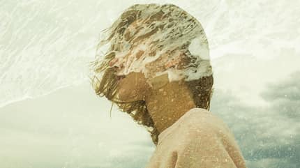 Frau mit vom Wind zerzausten Haaren am Meer Frau mit vom Wind zerzausten Haaren am Meer