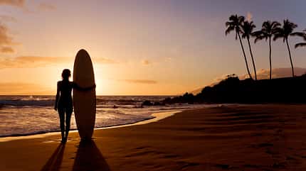 Silhouette von Frau am Strand mit Surfboard