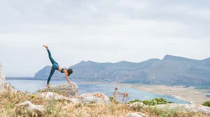 Junge Frau macht Yoga an einem Küstenaussichtspunkt Junge Frau macht Yoga an einem Küstenaussichtspunkt