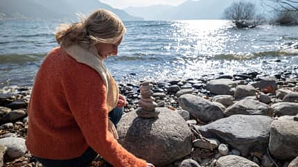 Frau sammelt Steine am See Frau sammelt Steine am See