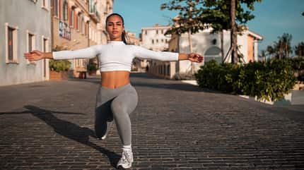 Trainierte junge Frau macht Fitnessübung in einer Gasse Trainierte junge Frau macht Fitnessübung in einer Gasse