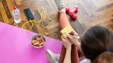 Junge sportliche Frau schreiben Trainingsplan in Notebook nach dem Training Junge sportliche Frau schreiben Trainingsplan in Notebook nach dem Training