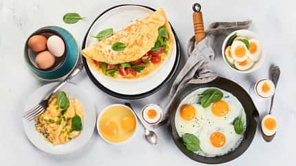 Tisch mit Spiegeleiern, gekochten Eiern und Omelette Tisch mit Spiegeleiern, gekochten Eiern und Omelette