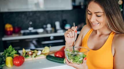 Sportliche Frau isst Salat