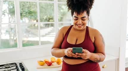 Kurvige Frau in Sportkleidung schaut auf ihr Handy