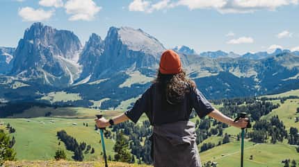 A woman is admiring the panoramic view of Seiser Alm on a sunny day