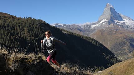 Young woman runs to mountain crest, sunrise